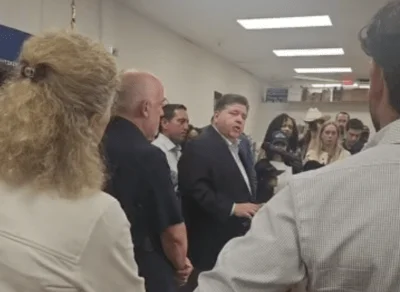 Gov. JB Pritzker stands surrounded by Texas Democrats during an August 3 press conference in DuPage County.