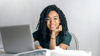 Medium happy ethnic woman sitting at table with laptop 1600x900